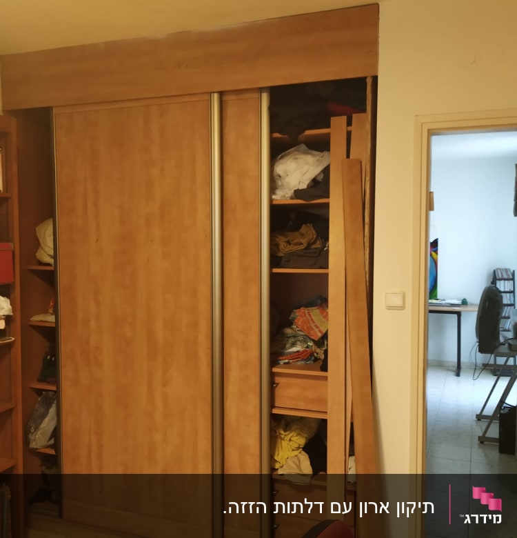 ארון עץ עם דלתות הזזה פתוחות וחלקי עץ בצד